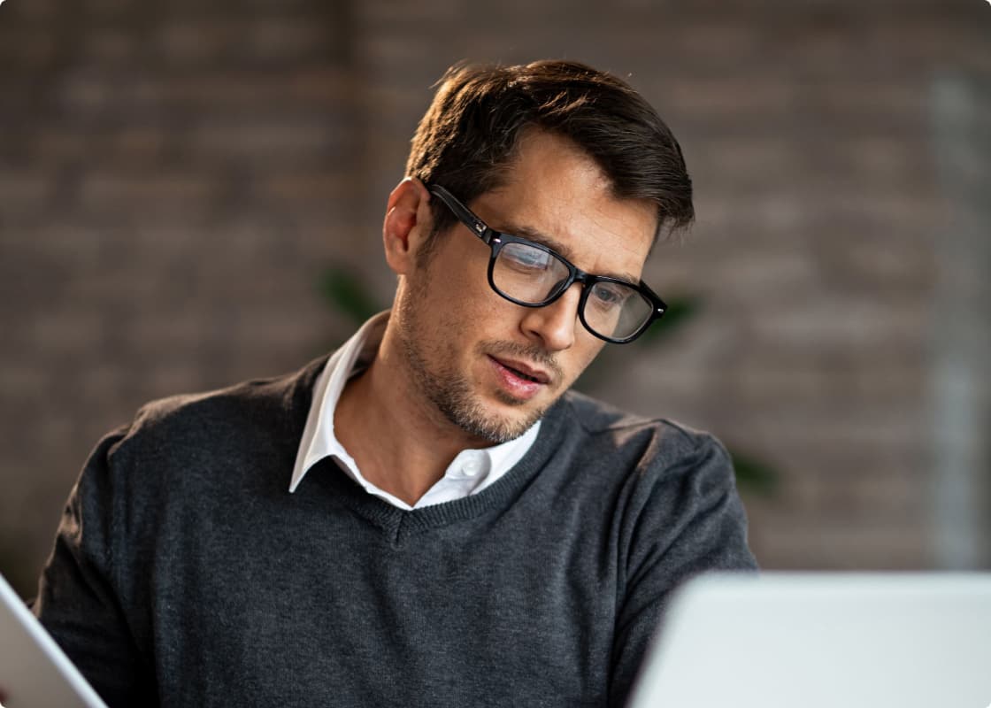 a guy taking notes with laptop in front