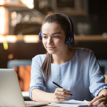 Woman in headphones taking down notes